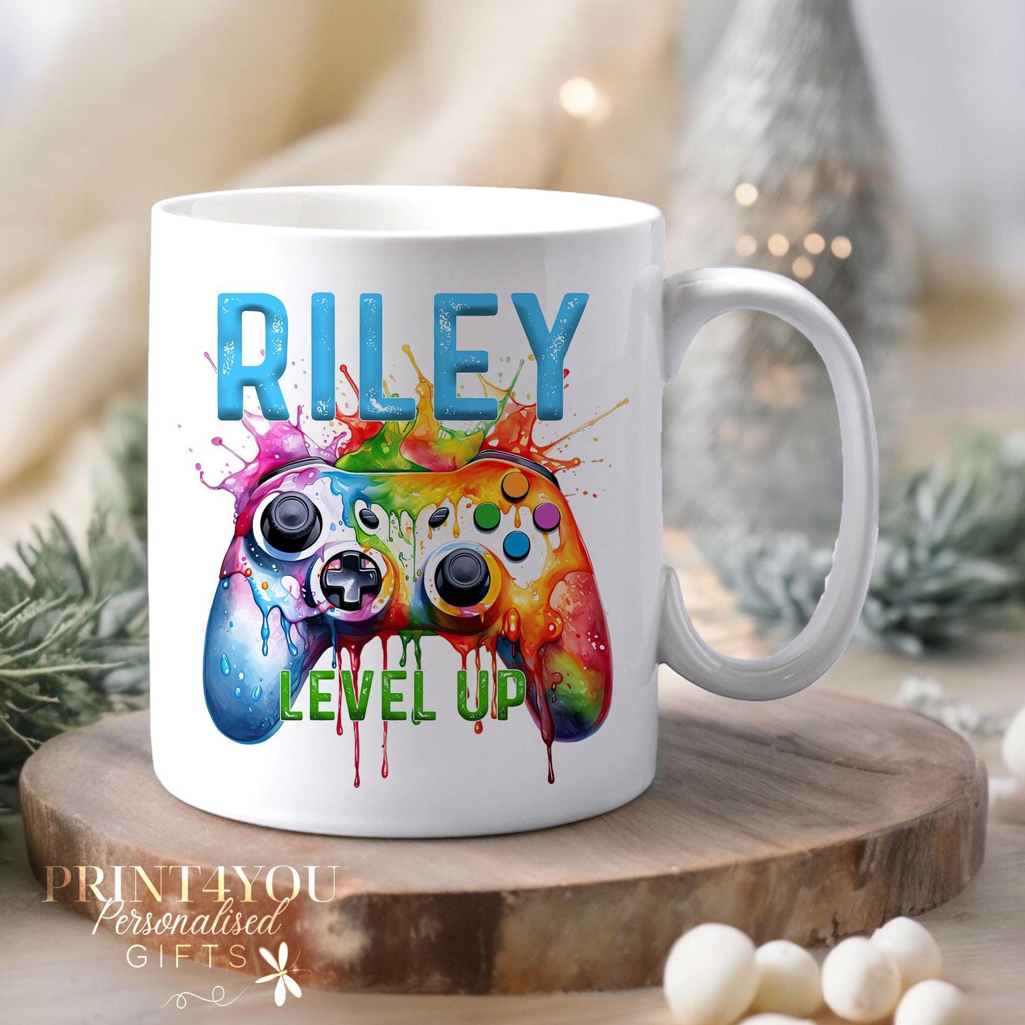 White ceramic mug personalised with a custom name, featuring a colourful splash-effect gaming controller design