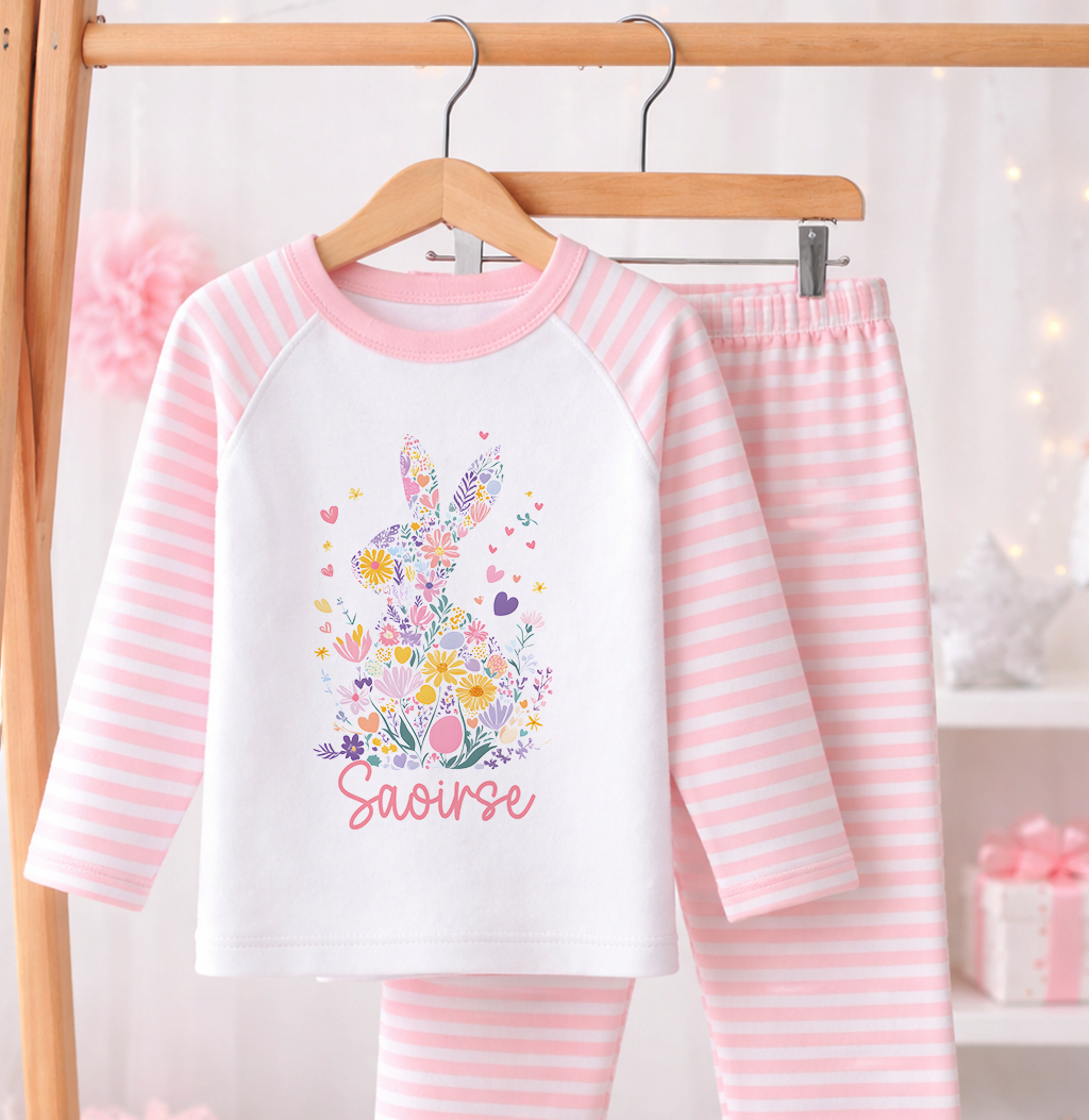 Pink and white striped pyjama set printed with a floral bunny design and personalised name, laid flat against a white background