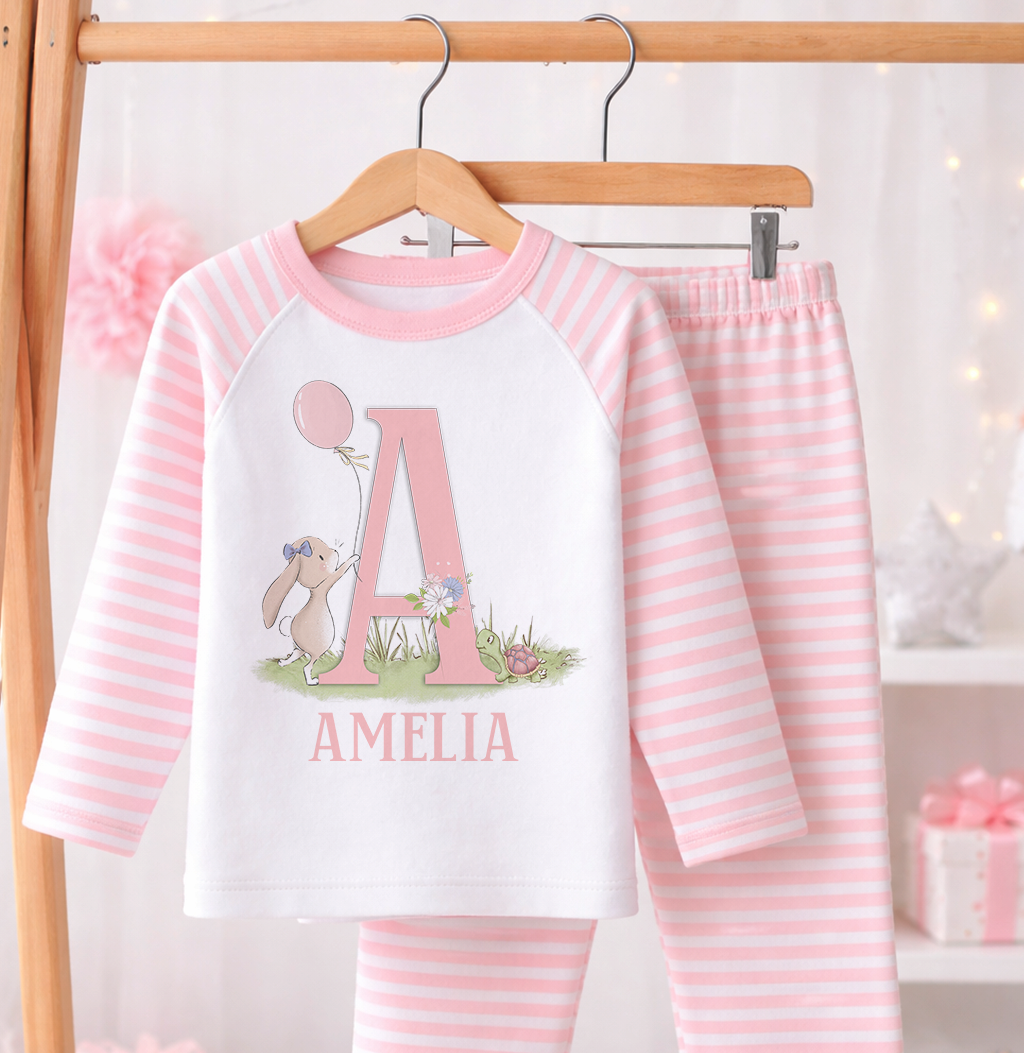 Pink and white striped pyjama set printed with a bunny design and personalised name, laid flat against a white background