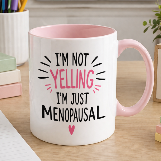 White ceramic mug with pink handle printed with the slogan I'm not yelling, I'm just menopausal