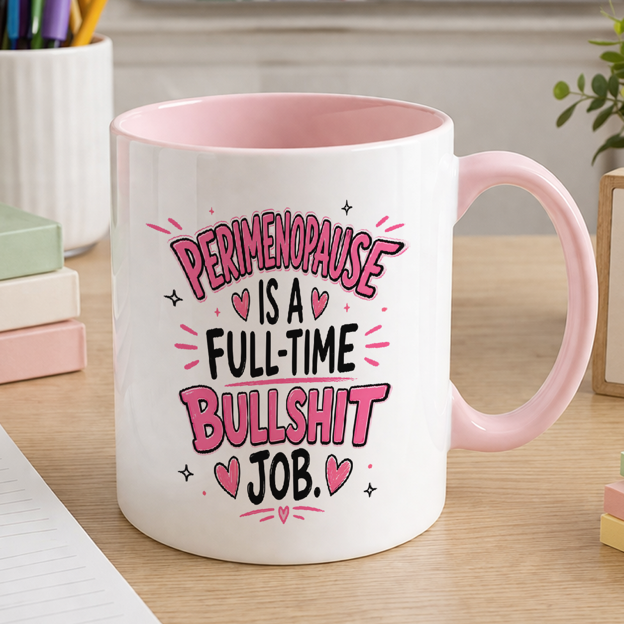 White ceramic mug with pink handle printed with the slogan Perimenopause is a full-time bullshit job