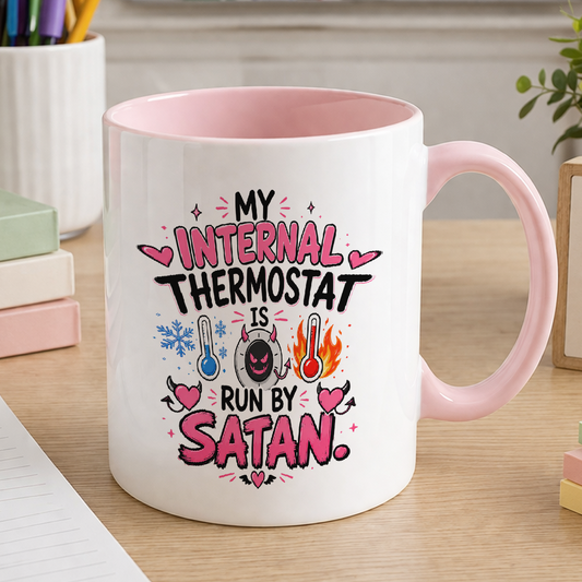 Pink handled ceramic mug printed with the funny slogan 'My internal thermostat is run by Satan', a novelty menopause gift