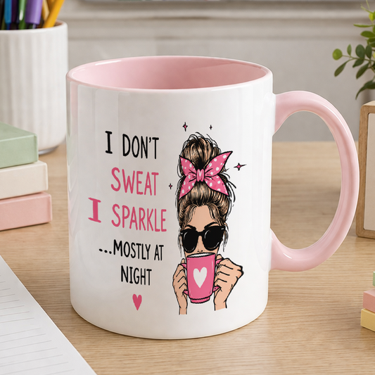 White ceramic mug with pink handle and pink inner, printed with sparkle illustrations and the text I don't sweat, I sparkle mostly at night