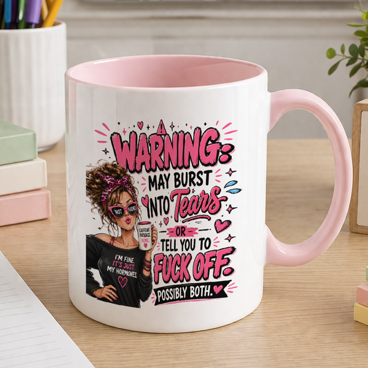 White ceramic mug with pink handle and pink inner, printed with the text Warning may burst into tears then tell you to fuck off