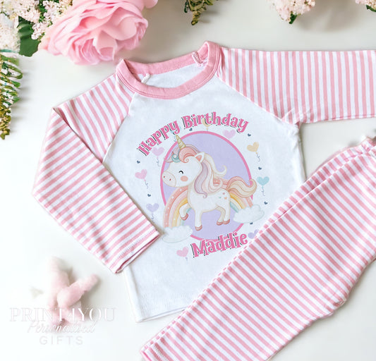Pink and white striped pyjama top with a unicorn, rainbow, heart and balloon birthday design, personalised with a custom name.