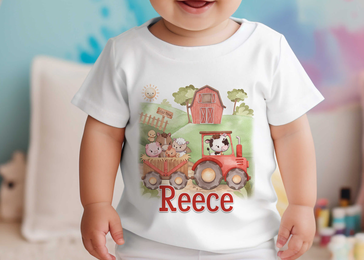 Toddler wearing a white T-shirt printed with a red tractor carrying farm animals and the personalised name Reece, against a blue background.