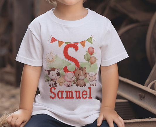 Toddler boy wearing a white t-shirt printed with a red letter S, bunting and farm animals, personalised with the name Samuel.