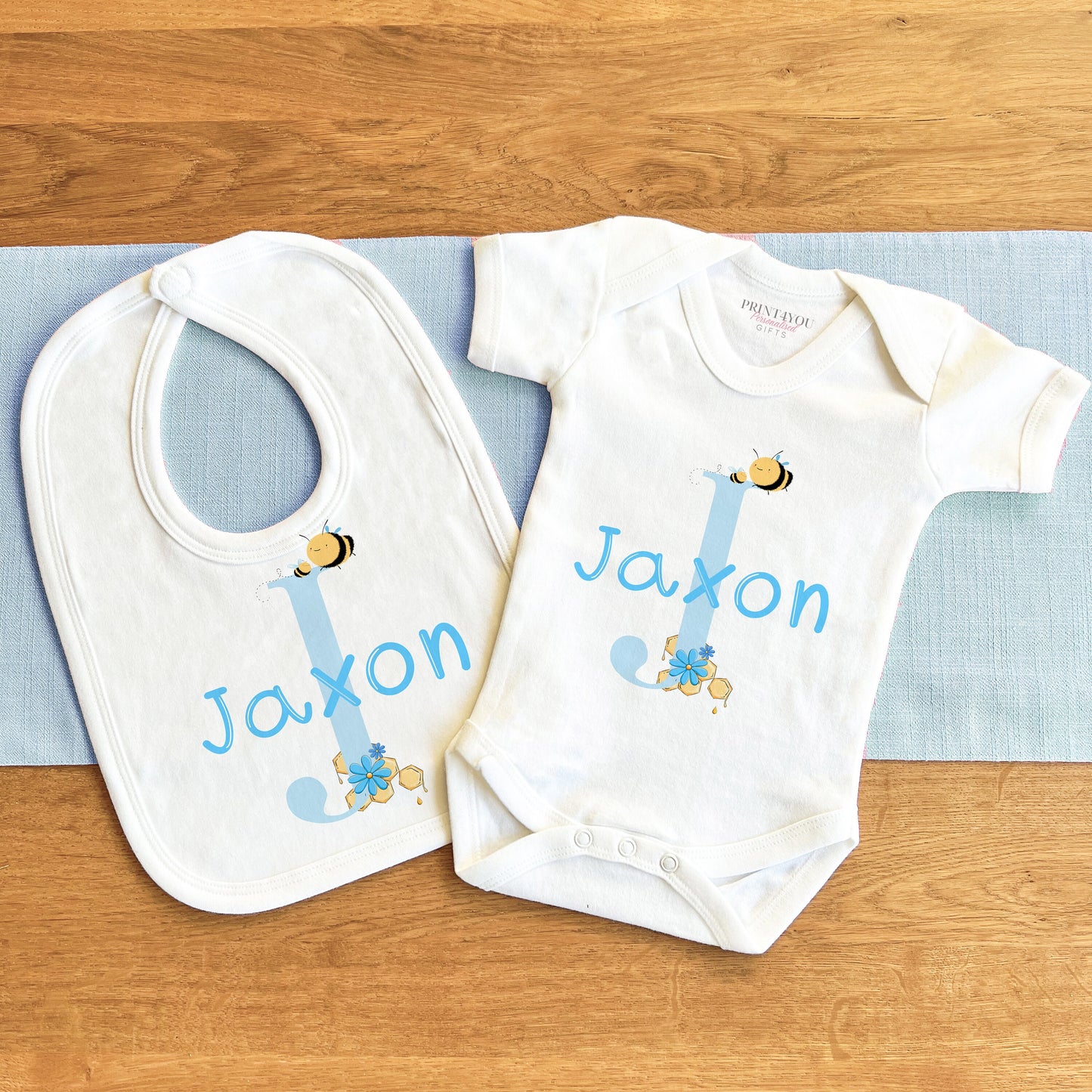 Personalised blue alphabet letter bumble bee bodysuit with baby name printed on the front.