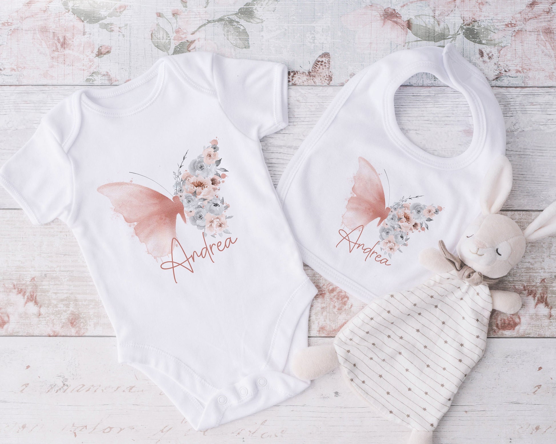 Blush butterfly personalised bib shown as part of a new baby gift set.