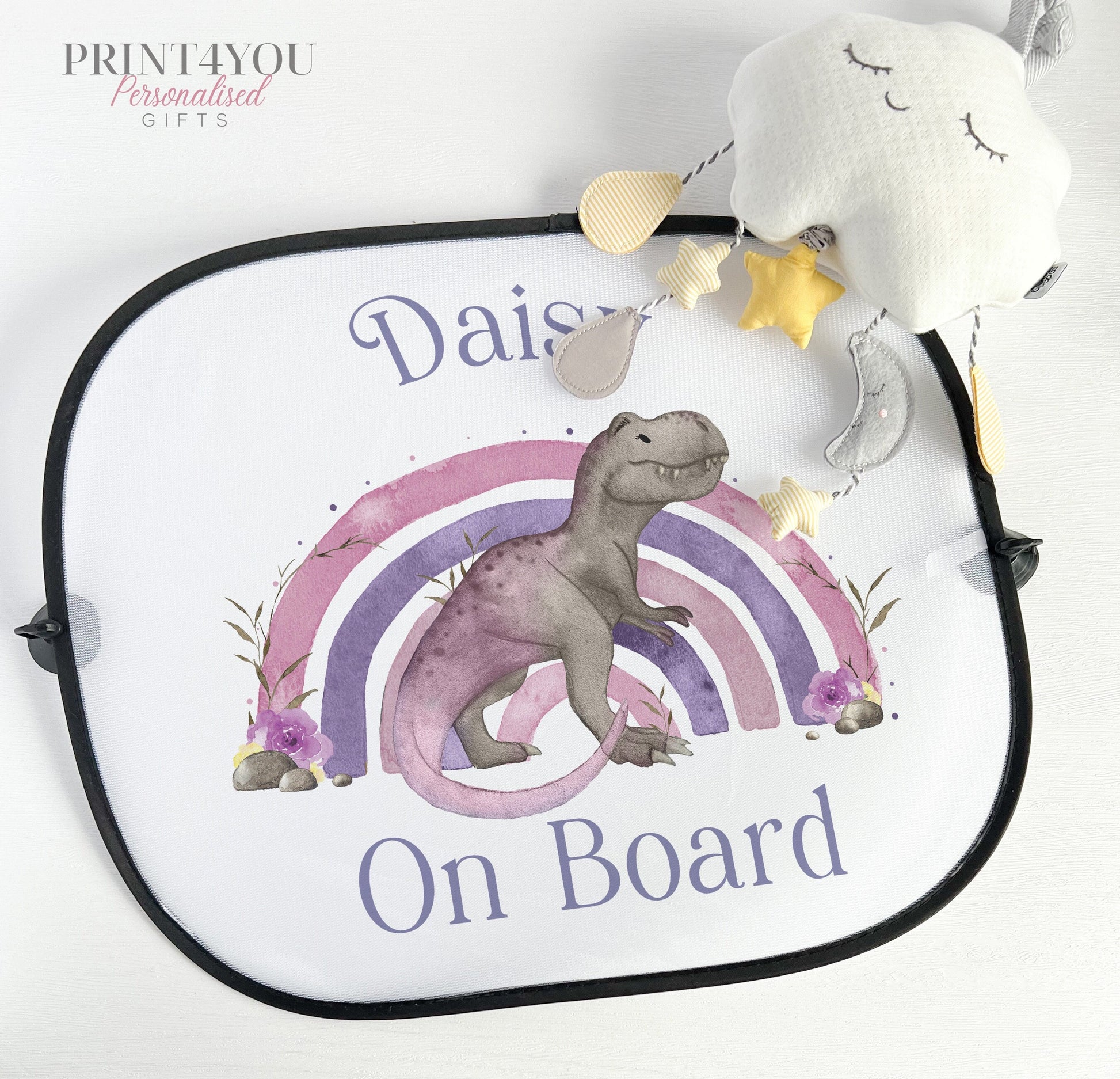Black-edged car window sun shade printed with a purple dinosaur, pastel rainbow and personalised text reading Daisy on Board.
