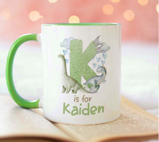 Light green trim ceramic mug printed with a dinosaur alphabet design and a personalised name