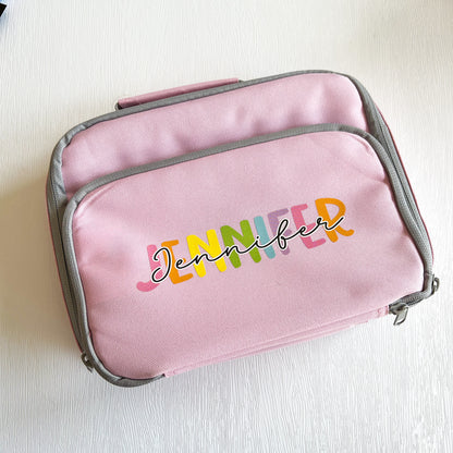 Pink insulated lunch cooler bag with front zip pocket, personalised with the colourful name Jennifer, top-down view.