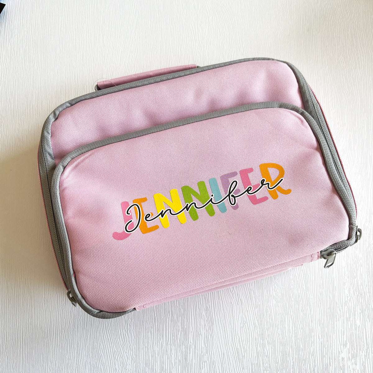 Rainbow insulated lunch cooler bag shown with padded grab handle.