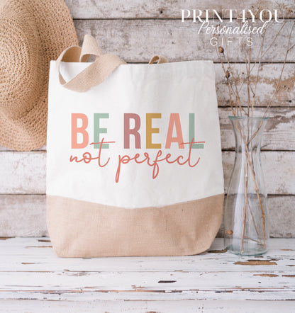 Cream and natural jute tote bag with the 'Be Real Not Perfect' slogan design, shown in the XL size.