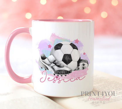 White ceramic mug with pink handle printed with a football and boots design and a personalised name