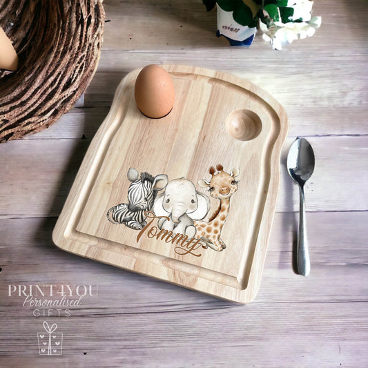 Wooden egg breakfast board with a boiled egg and spoon, personalised with a zebra, elephant and giraffe design and the name Tommy