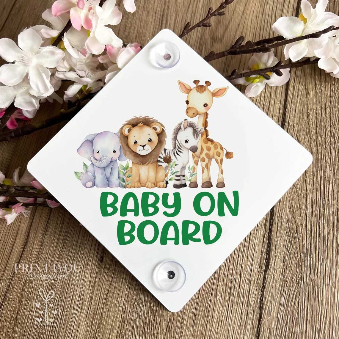 Diamond-oriented aluminium car window sign with suction cups, printed with a lion, zebra, giraffe and elephant safari design and the words 'Baby on Board'.