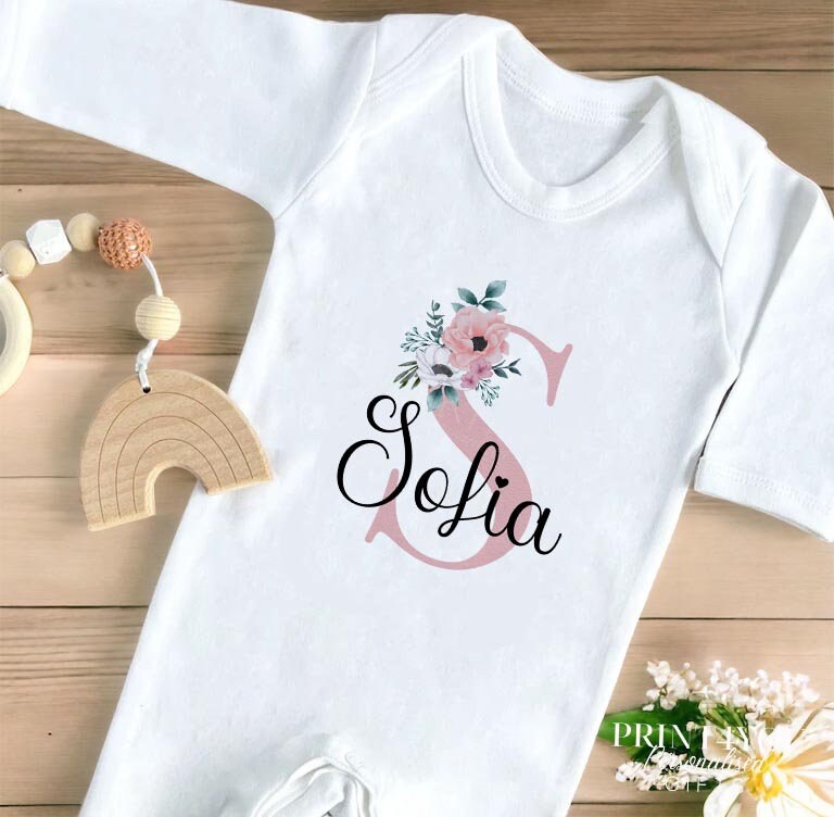 Personalised vest featuring pink floral print with initial letter and name, in soft white cotton.