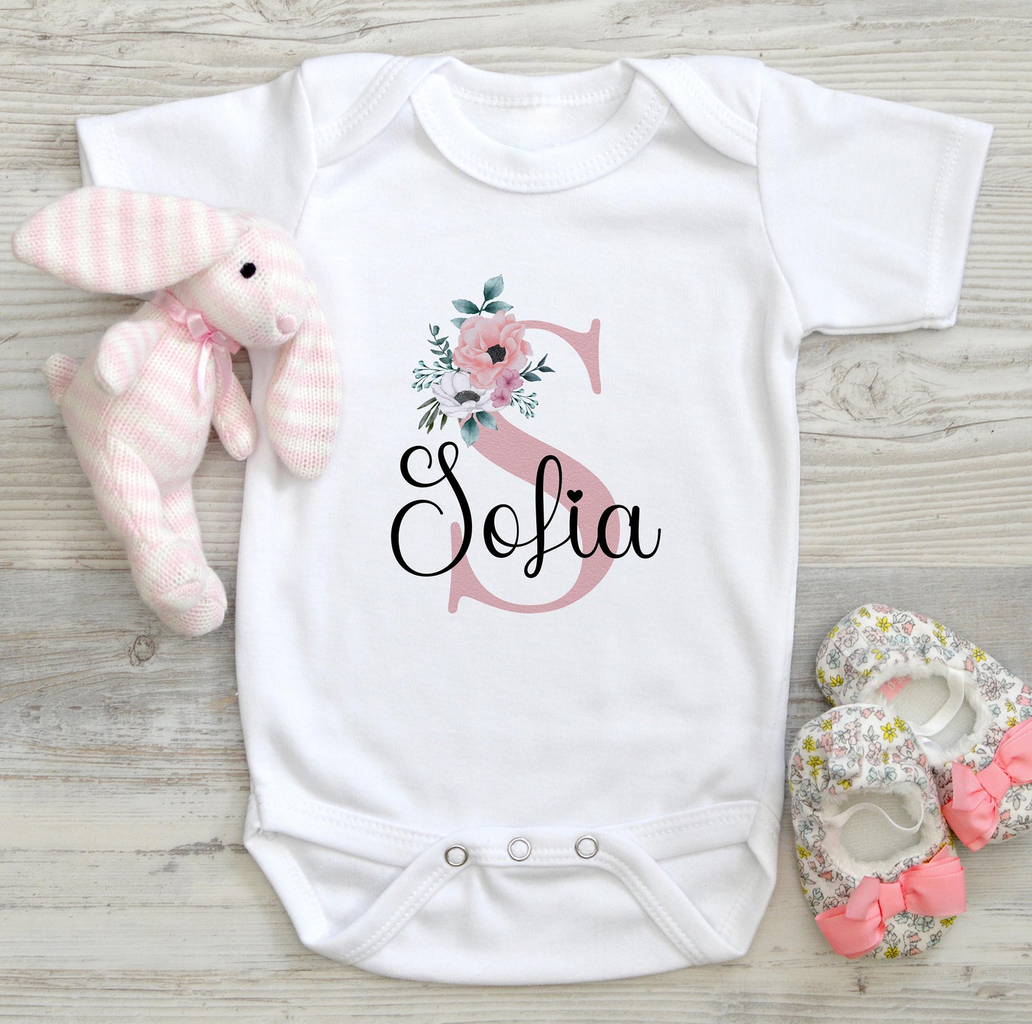 Personalised new baby bib printed with pink florals, an initial letter and baby's name.