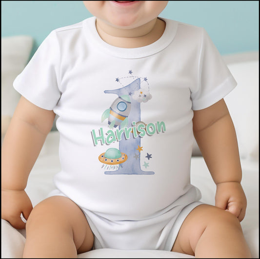 Personalised blue space rocket baby bib, printed with a custom name for a first birthday.