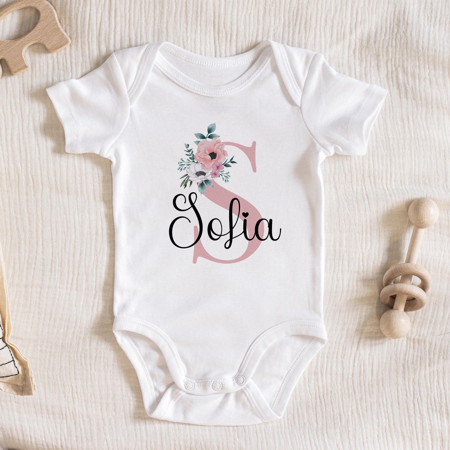 Personalised t-shirt printed with pink florals, initial letter and baby's name.