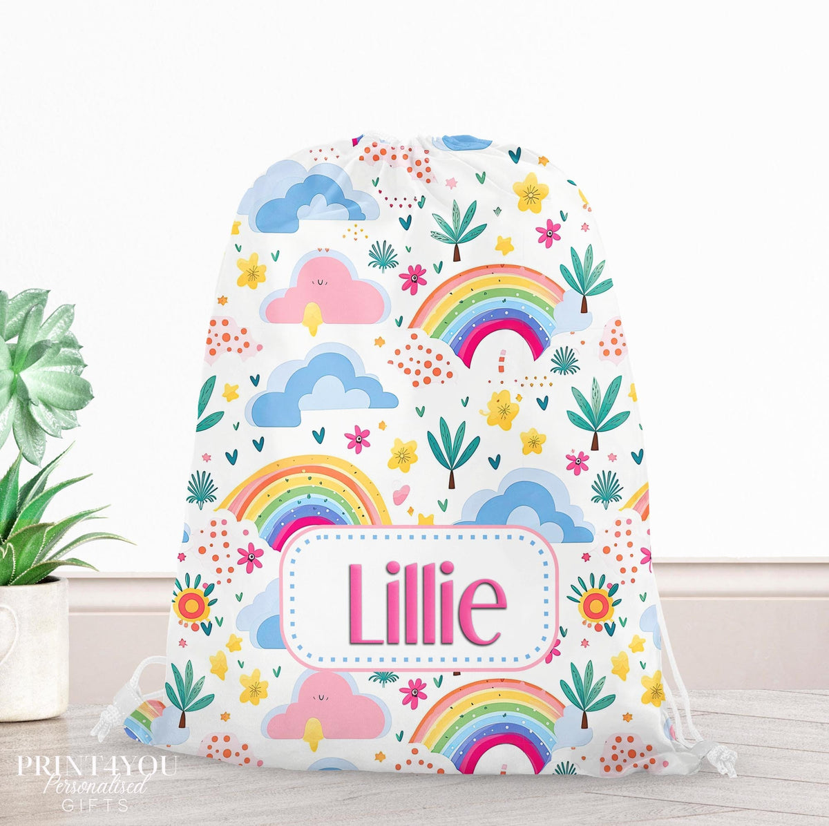 Cream drawstring PE bag printed with a colourful rainbow and clouds design, personalised with a child's name across the front
