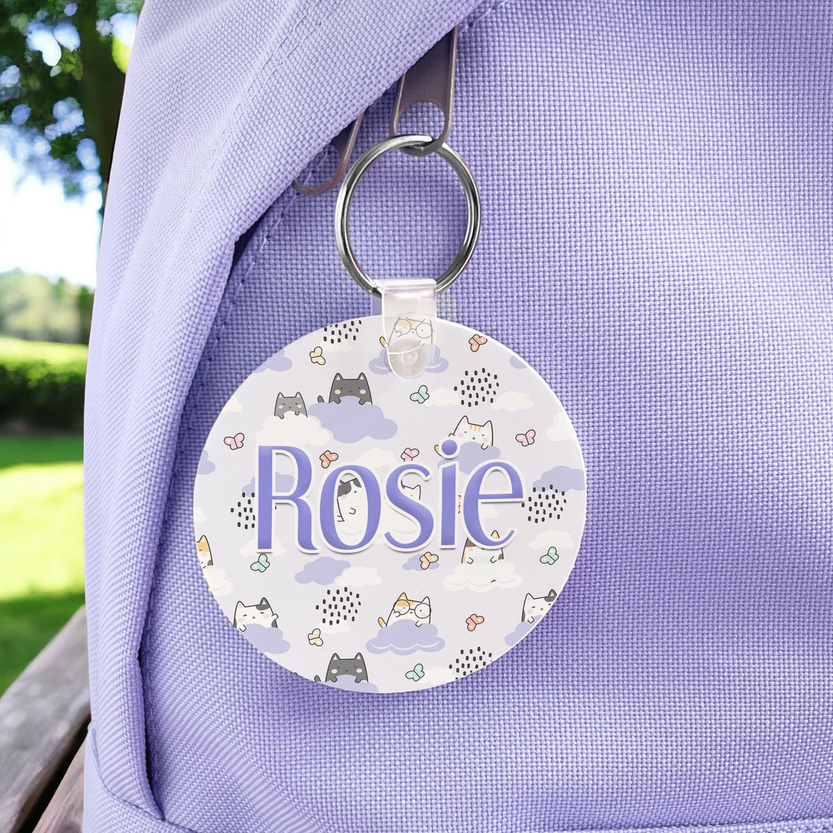 Round kawaii cats print bag tag on a keyring, personalised with the name Rosie, attached to a lilac backpack