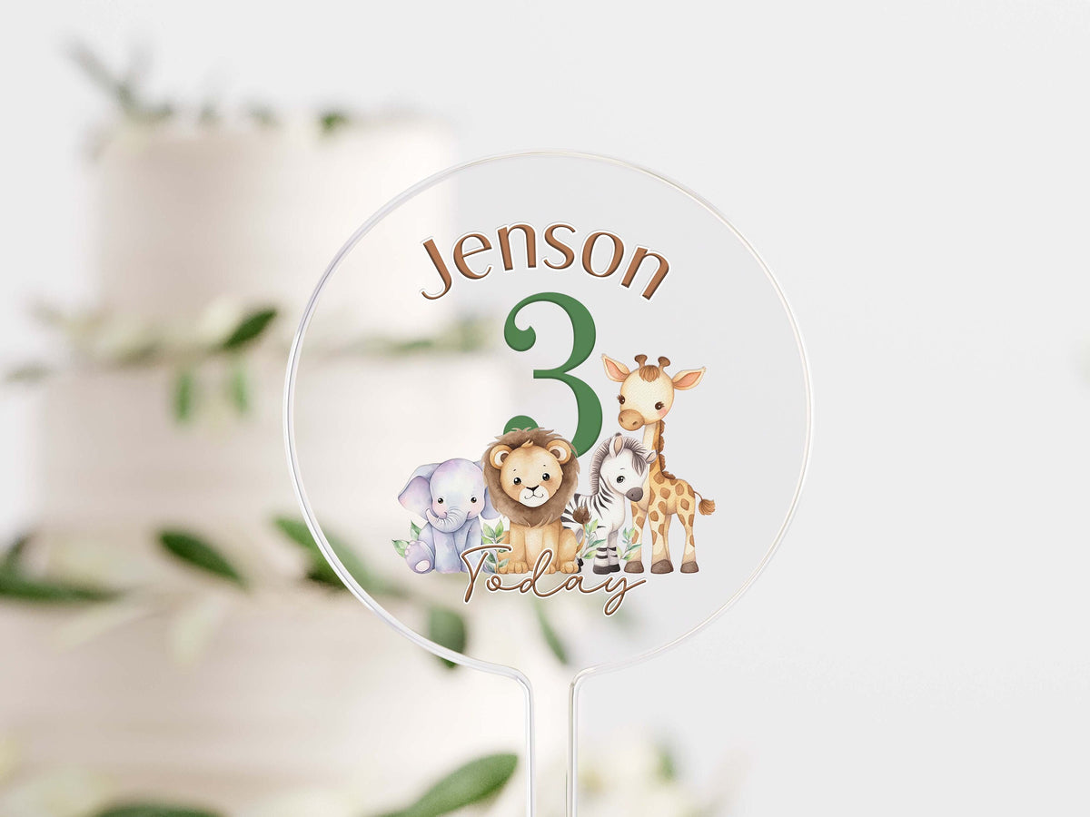 Clear acrylic cake topper UV printed with safari animals and personalised text, mounted on a stick for a birthday cake