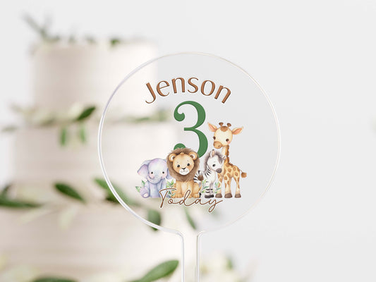 Clear acrylic cake topper UV printed with safari animals and personalised text, mounted on a stick for a birthday cake