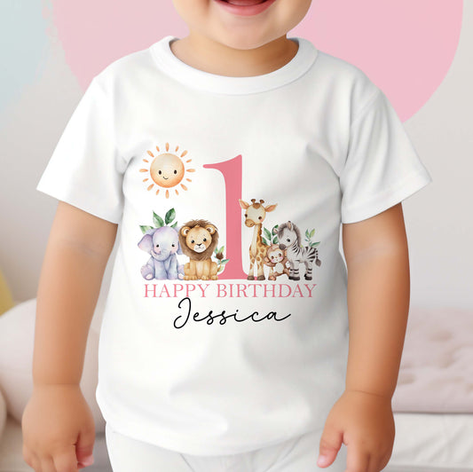 Personalised safari first birthday bib in soft white cotton, printed with lions, elephants and giraffes in pink text.