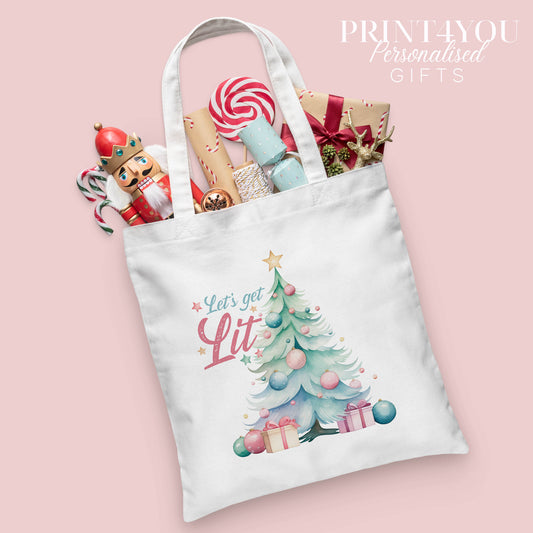 Christmas cotton tote bag printed with a decorated Christmas tree design and the words 'Let's Get Lit', shown packed with festive nutcracker and gift wrap props