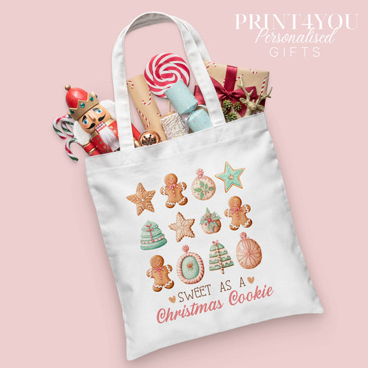 Personalised Christmas cotton tote bag printed with a gingerbread and Christmas cookie design and the words 'Sweet as a Christmas Cookie', shown packed with festive nutcracker and gift wrap props