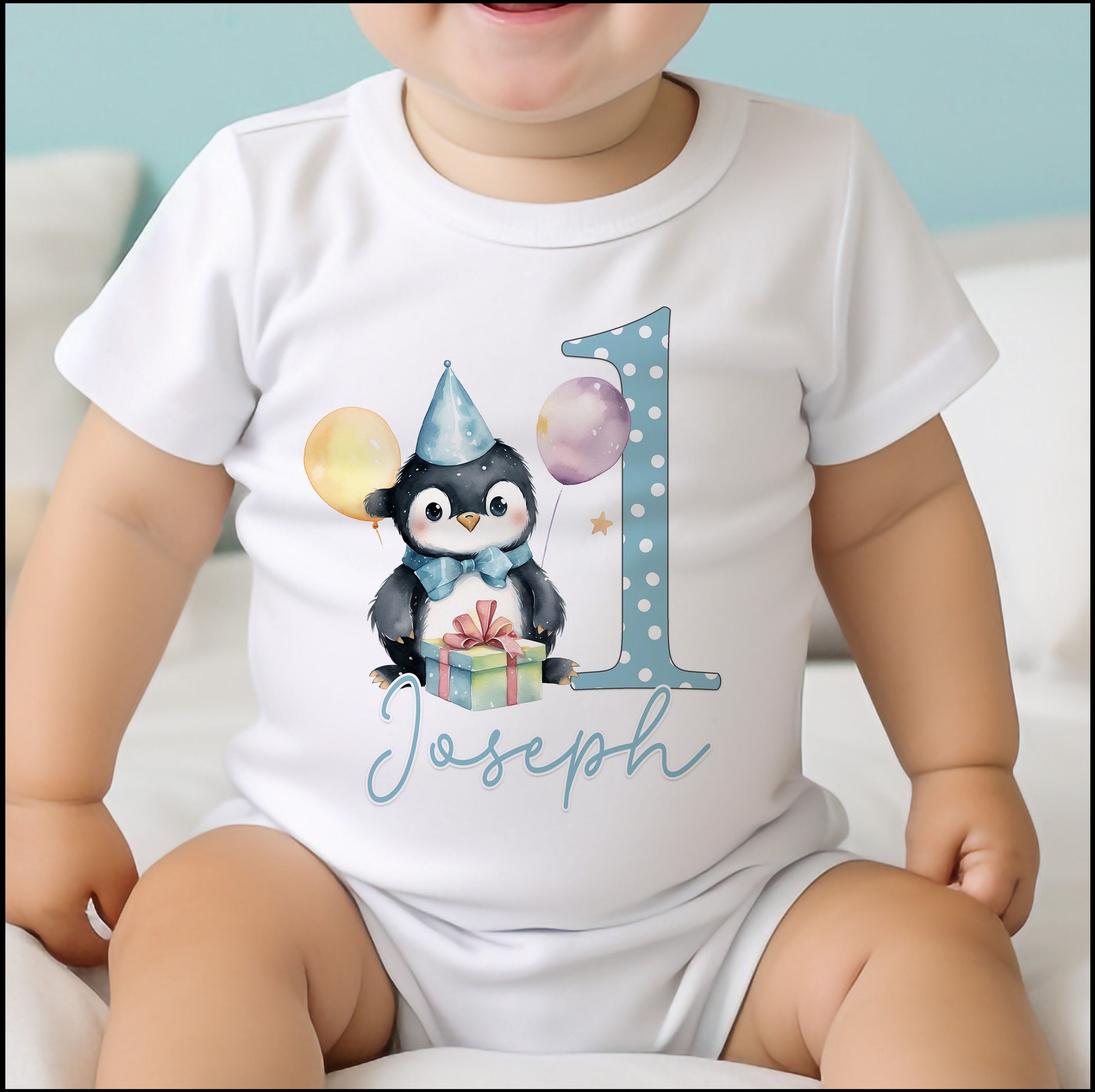 Personalised blue penguin bib laid flat, printed with the baby's name for a first birthday.