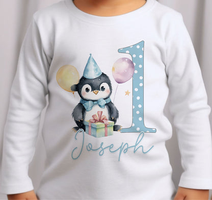 Personalised blue penguin first birthday outfit styled on a plain background.