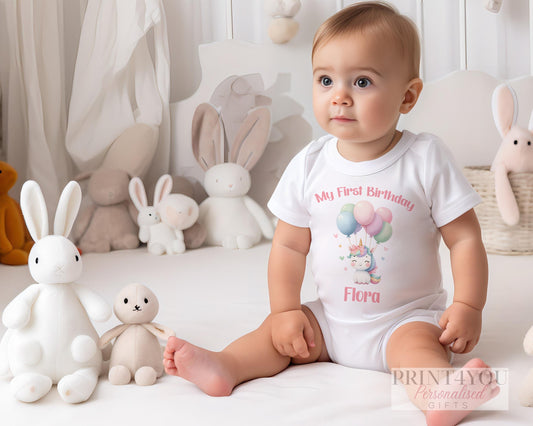 Personalised unicorn and balloons first birthday bib, printed with a custom name.